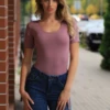 Soft fitted cotton T-shirt bodysuit with scoop neck, a plain tee that stays put under everything.