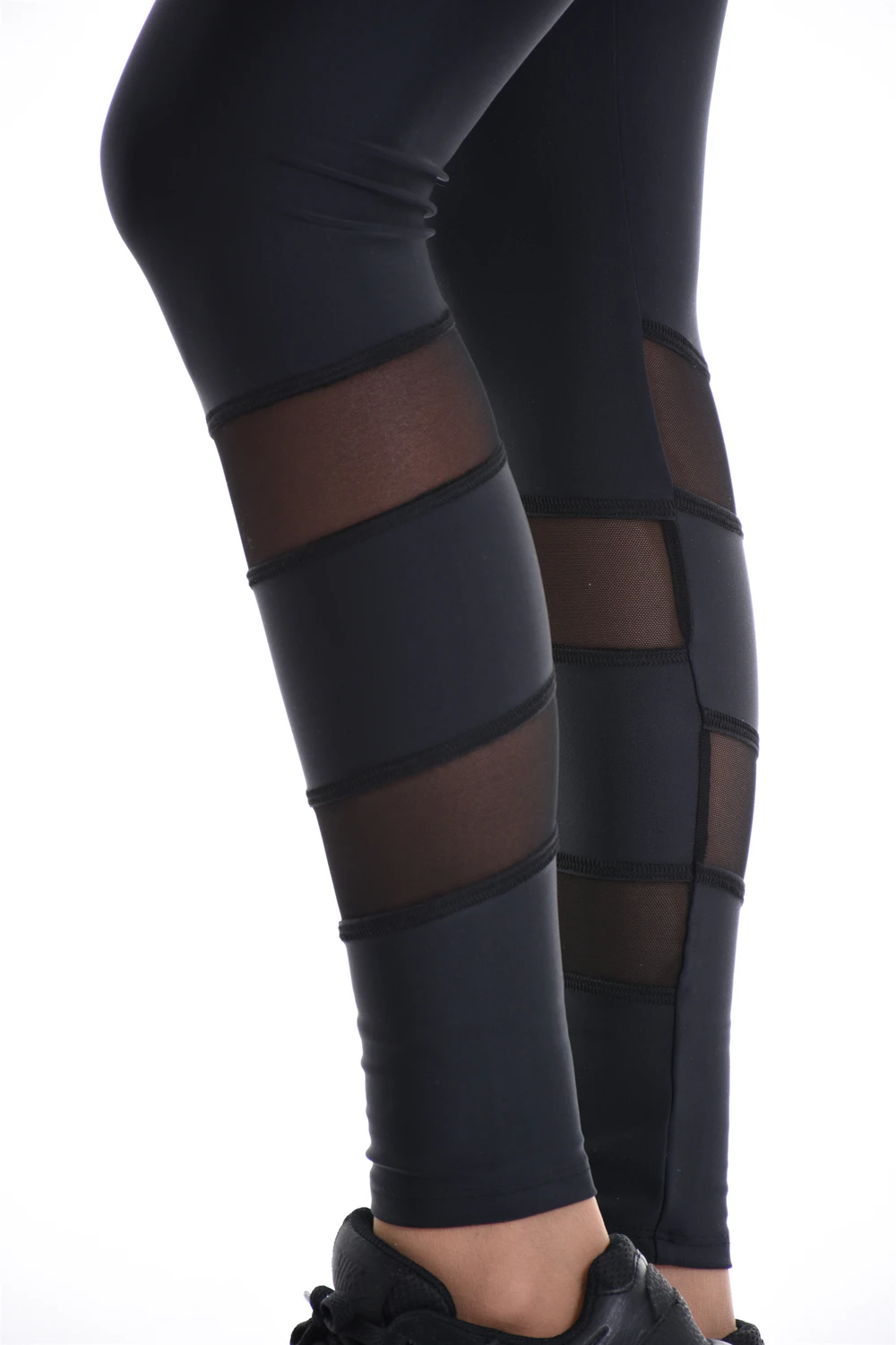 Close-up of black microfiber leggings showing the sheer mesh panels at the calf, fabric detail