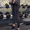 Black high-waisted microfiber leggings with a side mesh panel, side view in a gym setting