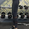 Black microfiber leggings with calf mesh panels, side view in a gym setting for active workouts