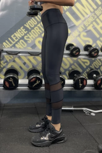 Black microfiber leggings with calf mesh panels, side view in a gym setting for active workouts