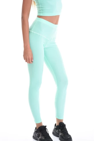 Reseda green microfiber leggings with a high crossover waistband, side view of the slim cut