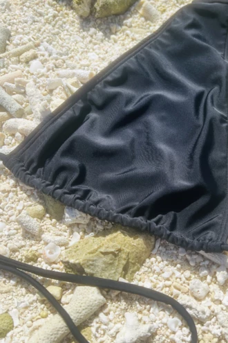 Black halter bikini top with a criss-cross lace-up at the center front that adjusts how open the deep V sits.