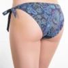 Blue paisley-print cheeky Brazilian bikini bottom with teal, purple and gold paisley over a blue base and bow ties.