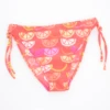 Girls' tie-side bikini bottom by Tiara Galiano in a citrus-slice print of oranges and lemons on a coral base, quick-drying polyamide.