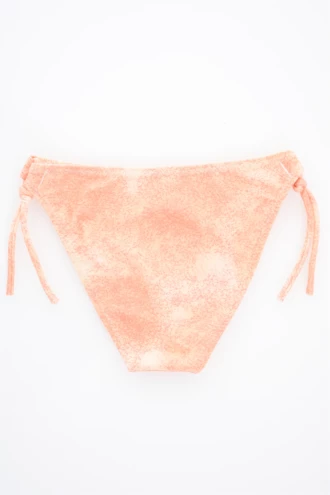 Washed-peach girls' swim bottom with adjustable side ties, softly stretchy quick-drying fabric for warm days outdoors.
