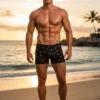 Men's black boxer-cut swim trunks with an all-over grey skull print, mid-rise fitted shape in quick-drying polyamide.